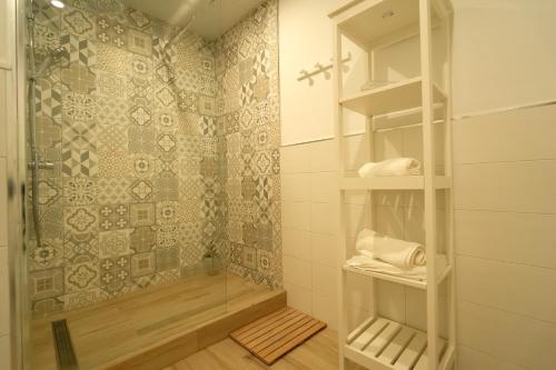 赫雷斯-德拉弗龙特拉Apartamentos Consistorio Live的带淋浴、卫生间和书架的浴室