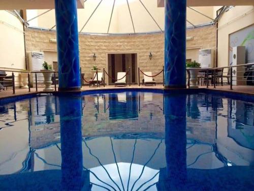 阿可贺巴فندق كارم الخبر - Karim Hotel Khobar的一座建筑物内一座拥有蓝色柱子的游泳池
