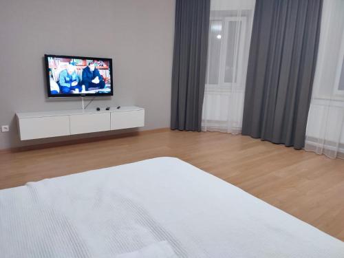 巴甫洛达尔Апартаменты Жаяу Мусы 7А的一间卧室配有一张床,梳妆台上配有电视