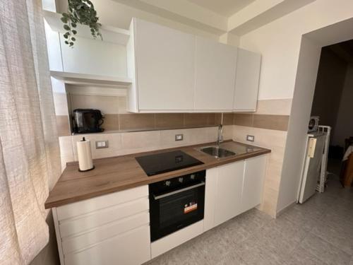 基亚拉瓦莱Affittacamere Il Cortile的厨房配有白色橱柜、炉灶和水槽。