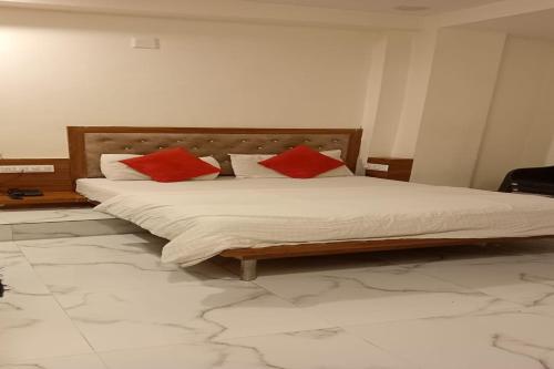 艾哈迈达巴德Hotel Sunrise Inn的一间卧室配有一张带两个红色枕头的床