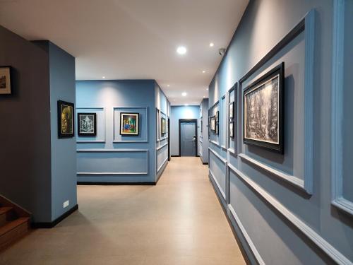 金边BKK Concept Hotel的走廊上设有蓝色的墙壁和墙上的绘画作品