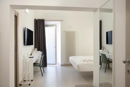 泰尔莫利Ruffini Rooms的白色卧室配有床、书桌和镜子