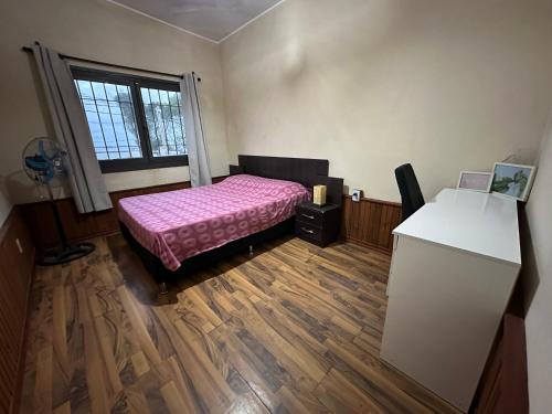 库奇拉阿尔塔Casa Alquiler Cuchilla Alta 1的一间卧室配有一张床、一张书桌和一个窗户。