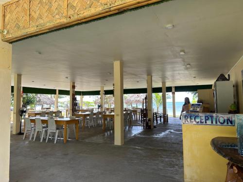 董索Dancalan Beach Resort的配有桌椅的餐厅,以及坐在柜台上的人