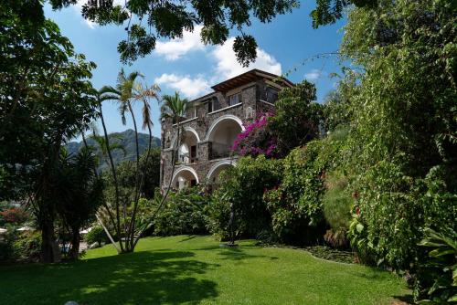 迪坡斯特兰Posada del Tepozteco - Hotel & Gallery的棕榈树花园中的古老石屋