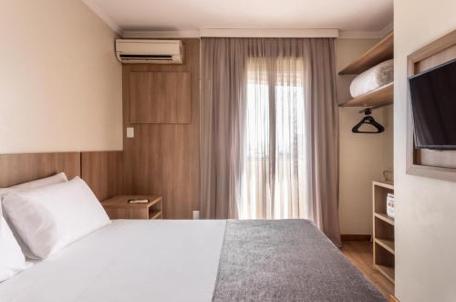 阿雷格里港阿雷格里港千禧蓝树酒店的卧室配有白色的床和窗户。