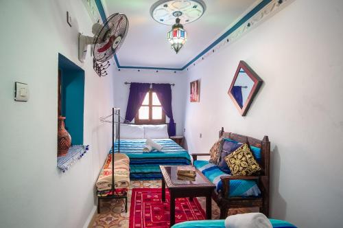 舍夫沙万Dar Chourafa Riad的一间卧室配有一张床、一张桌子和一个窗户。