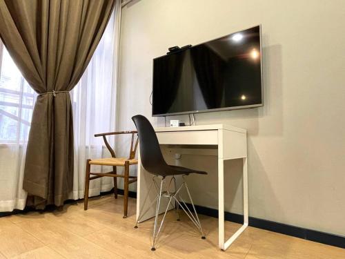 第比利斯Apart Hotel Console的一张桌子,墙上有一台电视,椅子