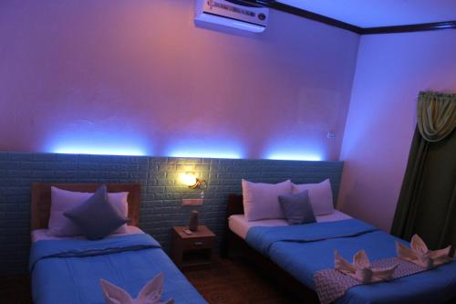 莫阿尔博阿Kojie Guest House的蓝色灯的客房内的两张床