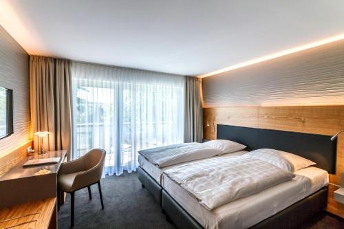 罗拉赫Hotel Villa Elben Lörrach bei Basel的一间卧室配有一张床、一张书桌和一个窗户。