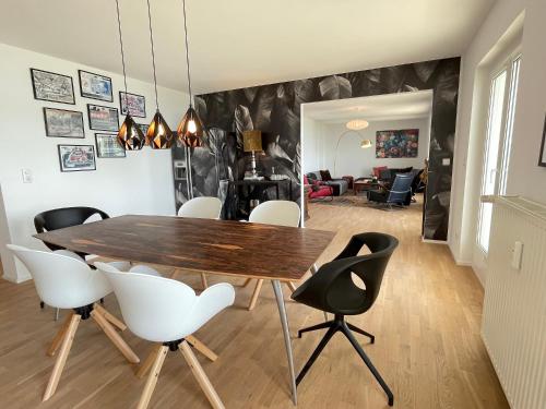 洛豪SUNSET Apartment direkt am Bodensee mit Parkplatz的一间带木桌和白色椅子的用餐室