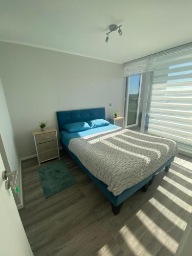 塔尔卡瓦诺Depto nuevo en brisas del sol的一间卧室设有蓝色的床和窗户。