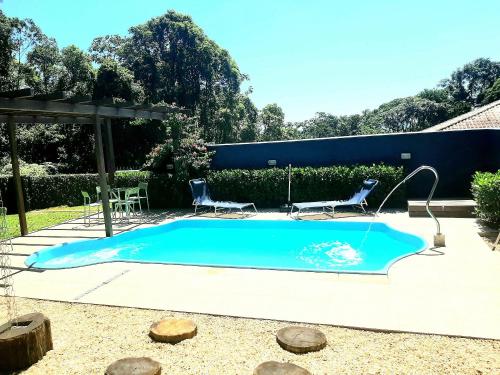 伊达贾伊Casa Green Piccoli - Itajaí/SC的一个带两把椅子和水滑梯的游泳池