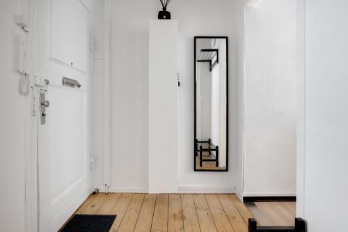 哥本哈根Perfectly located cozy apartment的走廊上设有白色的墙壁和一面镜子