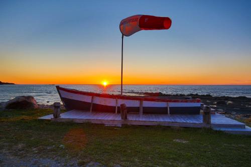 Petite-ValléeMaison LeBreux - Motel的日落时在海滩上悬挂国旗的船只