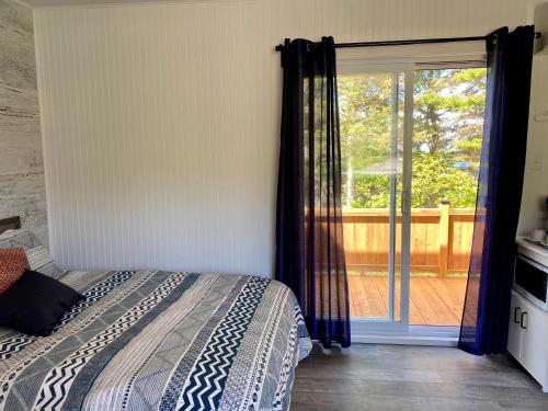 Petite-ValléeMaison LeBreux - Motel的一间卧室设有一张床和一个滑动玻璃门