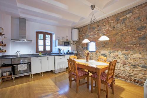 Les Franqueses del VallèsMas Can Calet Aparthotel的厨房配有木桌和石墙