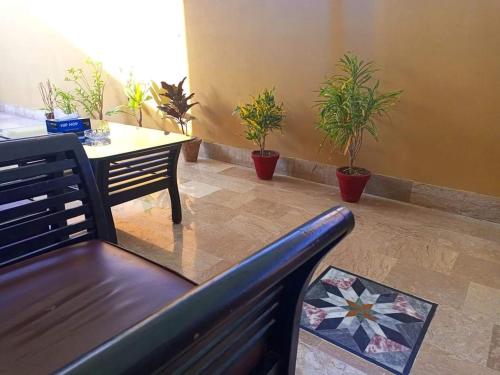 卡拉奇Furnish Rooms Near Jinnah Airport的客厅配有长凳、桌子和盆栽植物