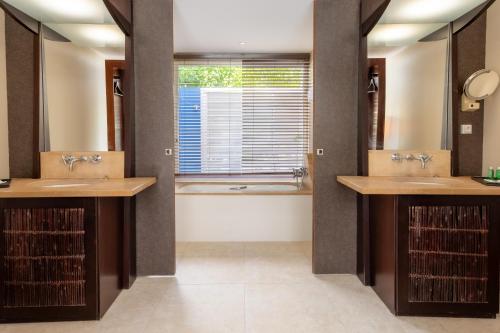 勒弗朗索瓦Physacap Suites & Villas的浴室配有两个盥洗盆和浴缸。