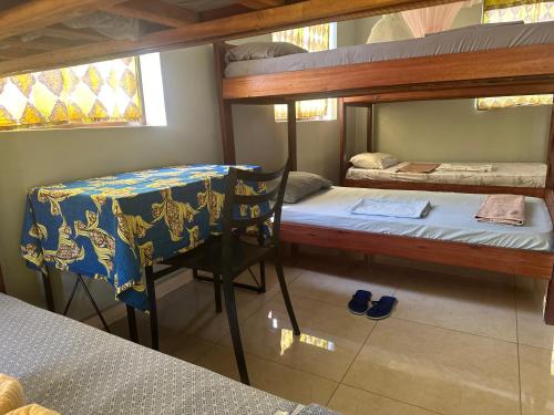 AruaMissions Cafe Arua - GuestHouse的客房设有两张双层床、一张桌子和一把椅子。