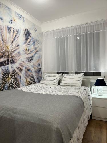 托伦Apartament Rubinowy的卧室配有一张挂着蒲公英壁画的床。