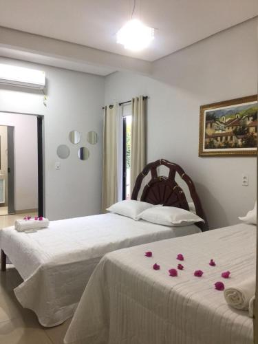 帕尔马斯HOSTEL D´ SALLES (PRÓXIMO AO AEROPORTO)的卧室内的两张床,卧室的床单上摆放着玫瑰花