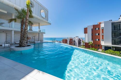 福恩吉罗拉Serene Seaview Retreat in Higueron: 2BR Oasis的棕榈树建筑屋顶上的游泳池
