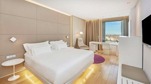 马德里马德里欧式建筑NH精选酒店的一间酒店客房,配有一张白色的床和一张书桌