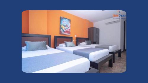 内瓦Hotel Sevilla Neiva的橙色墙壁客房的两张床