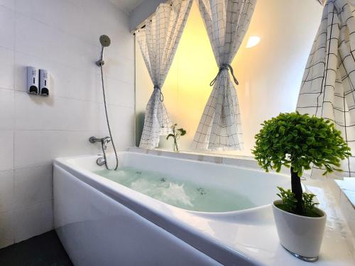 新山Loft Suite JB Town near CIQ 7Pax的一间带浴缸的浴室,里面装有植物