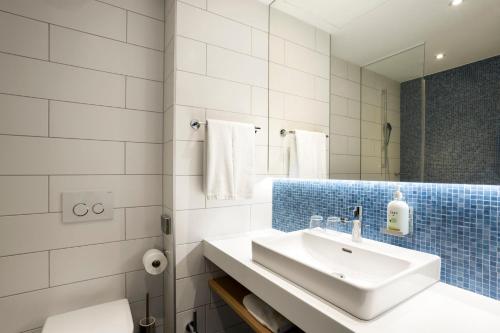 慕尼黑慕尼黑市西智选假日酒店的白色的浴室设有水槽和镜子