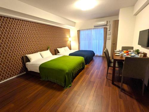 大阪ESLEAD HOTEL Namba Ebisu West的酒店客房设有两张床、一张桌子和一张书桌。