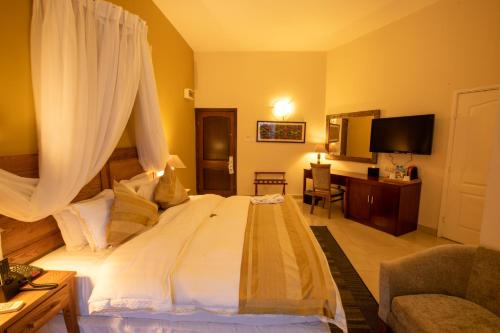 阿克拉La Palm Royal Beach Hotel的卧室配有带窗帘的大型白色床