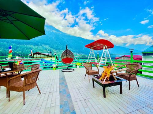 马拉里TATA Vista Resort Mall Road Manali - Centrally Heated & Air Cooled的庭院配有桌椅和遮阳伞。