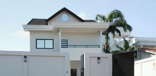 Abomey-CalaviVilla luxueuse的一间白色的房子,有两个车库门和棕榈树