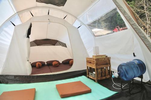 PalayanganSoraCai Riverside Campsite的帐篷配有一张床和一张桌子
