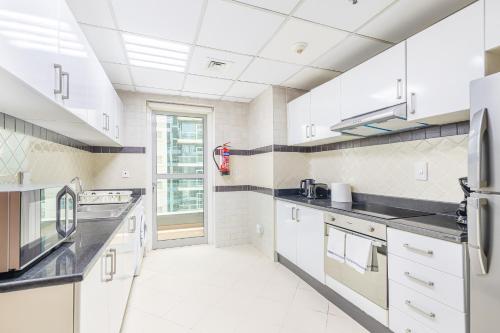 迪拜Elegant 3BR in JBR w/ partial Marina View的一间大厨房,配有白色橱柜和黑色台面