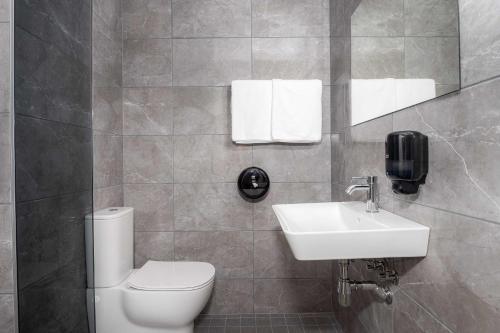 派尔努Hotell Tammsaare的一间带卫生间、水槽和镜子的浴室