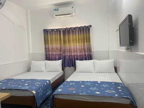 胡志明市Thanh Hương Hotel的带电视的小型客房中的两张床