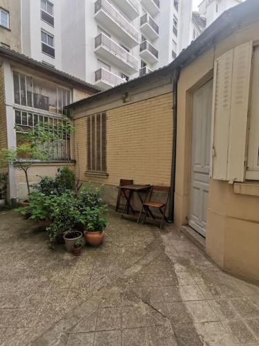 巴黎A nice little studio in the beautiful Paris.的一座庭院,旁边是桌子和盆栽植物