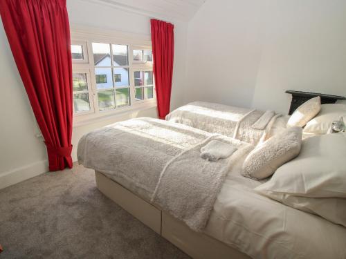 雷克瑟姆8 New Houses的一间卧室设有两张床,窗户配有红色窗帘