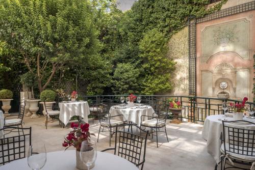 马德里Relais & Châteaux Hotel Orfila的户外庭院配有桌椅和树木。