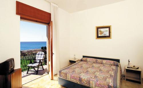 罗切拉伊奥尼卡吉安弗兰科公园酒店的一间卧室设有一张床和一个海景阳台