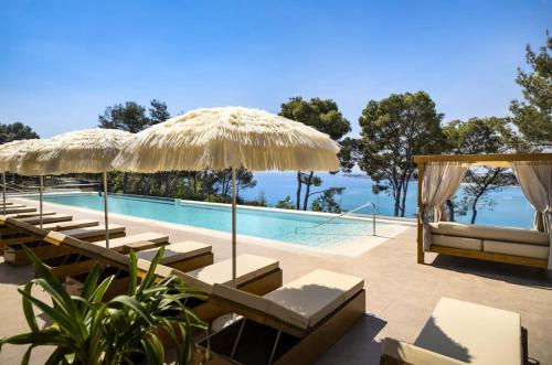 波雷奇Camping Lanterna Premium Resort - Vacansoleil Maeva的一个带椅子和遮阳伞的游泳池的度假酒店