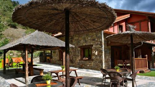 EnterriaApartamentos Rurales & Spa La Bárcena的房屋前设有带桌子和遮阳伞的庭院。