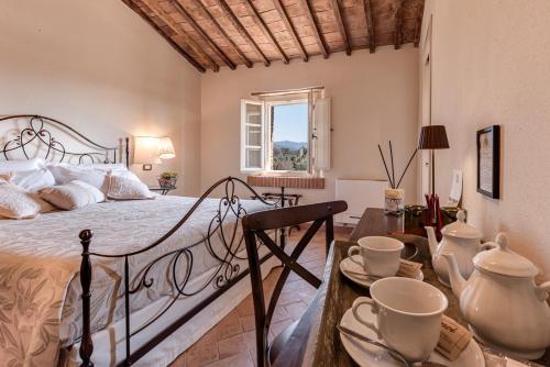 比博纳Locanda dell'Aioncino的一间卧室配有床和桌子,上面有杯子