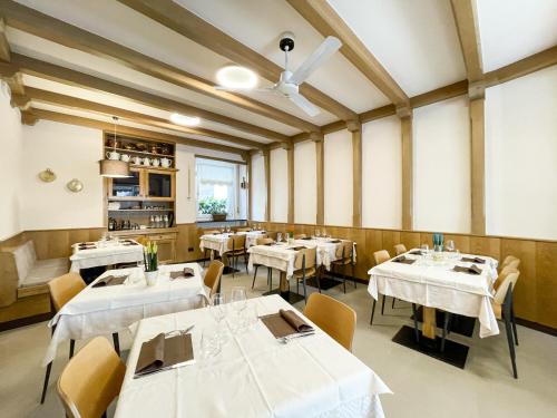 莱德罗Hotel Locanda Alla Perla的一间设有白色桌椅的用餐室
