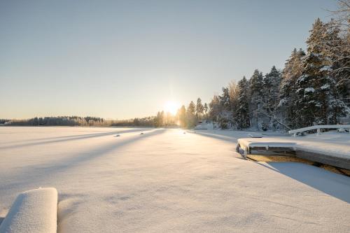 Asikkala雷蒙卡基度假酒店的一条有雪覆盖的道路,在背后有太阳
