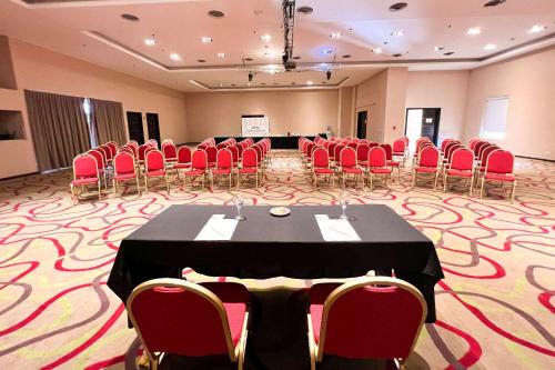 富内斯Howard Johnson Hotel & Resort Funes的一间会议室,配有桌子和红色椅子